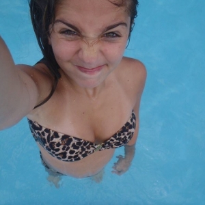 Meisje trekt gekke bek als ze selfie maakt in het zwembad